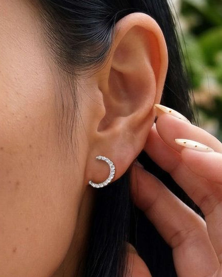 A close-up lifestyle shot of a woman wearing a delicate silver crescent moon necklace and matching crescent hoop earrings.